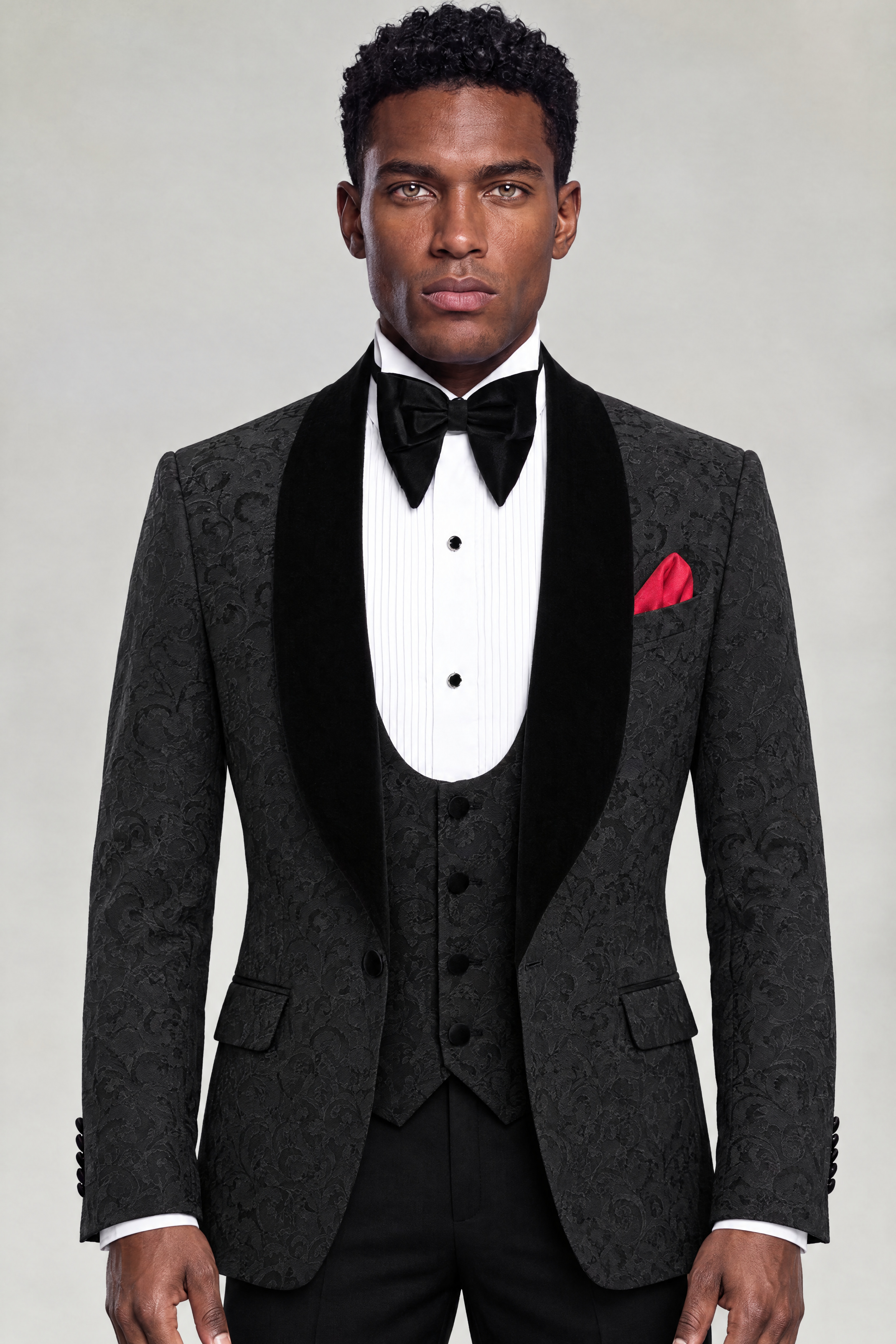 Front portrait of a black damask tuxedo with velvet shawl lapels, matching four-button vest and black trousers from Gentleman's Guru