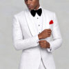 Model adjusting his cuff in a white floral wedding tuxedo with white satin shawl lapels from Gentleman's Guru