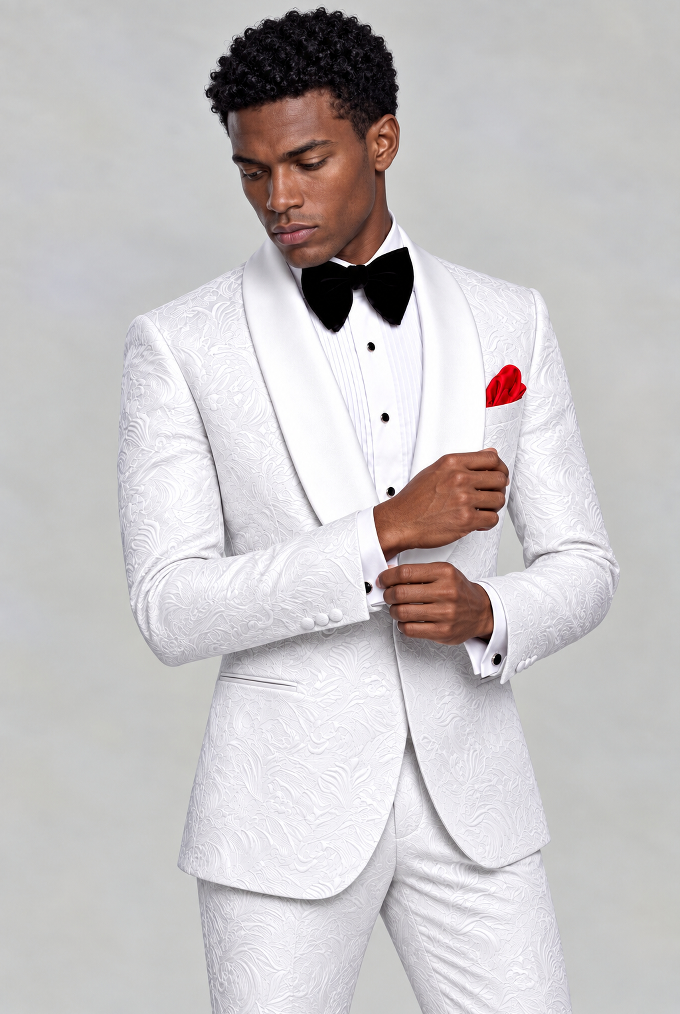 Model adjusting his cuff in a white floral wedding tuxedo with white satin shawl lapels from Gentleman's Guru