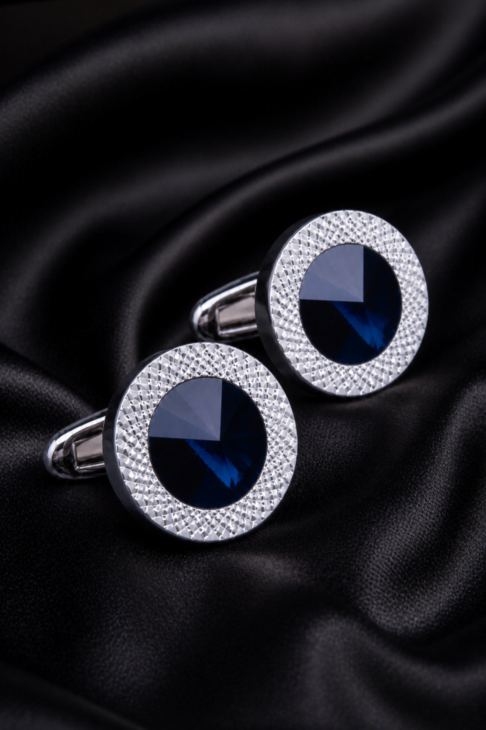 Luxury round blue crystal cufflinks displayed on silk
