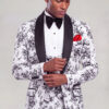 Model adjusting the cuff of a floral tuxedo with black satin shawl lapels and matching vest from Gentleman's Guru