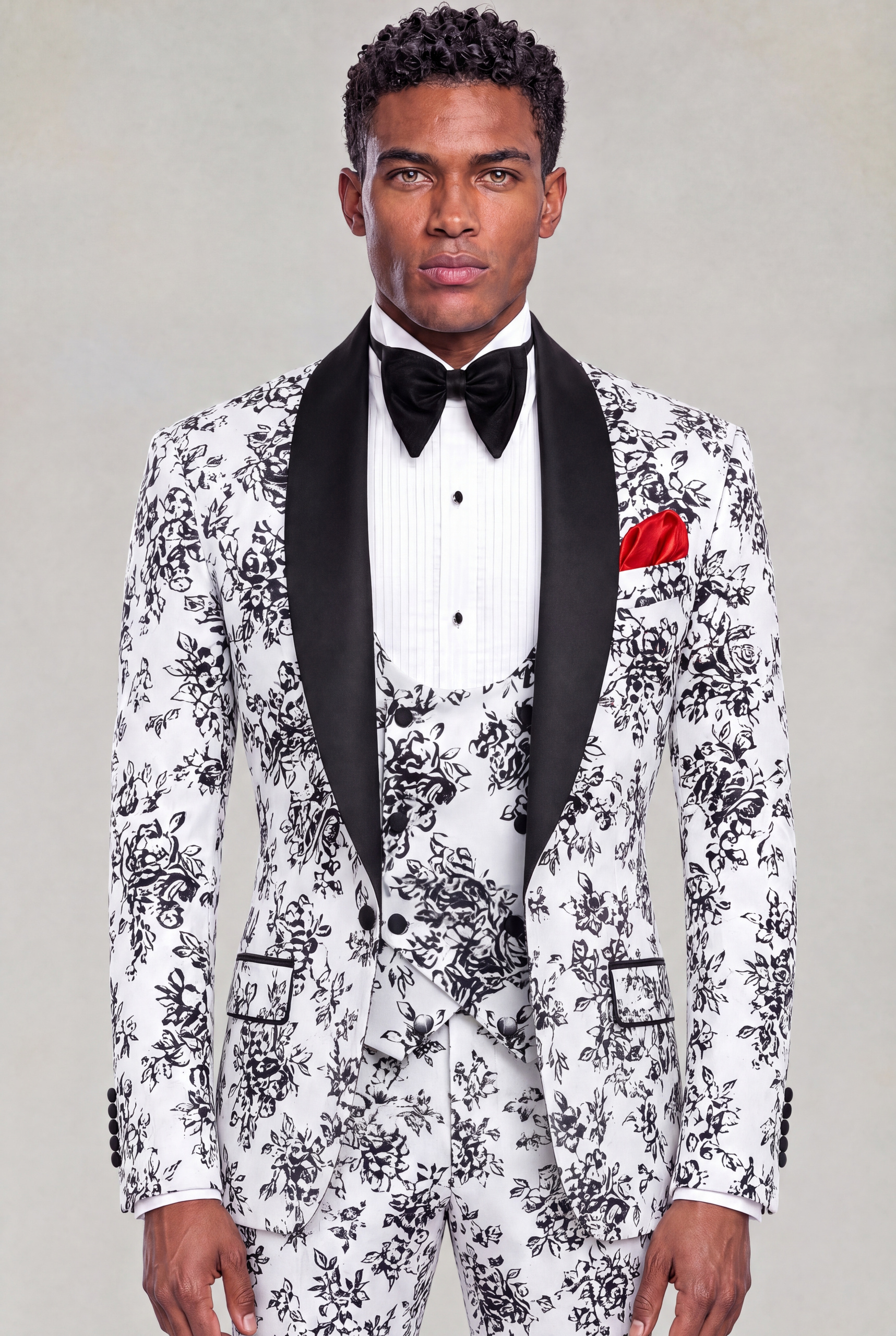 Front portrait of a white and black floral three-piece tuxedo with black satin shawl lapels and red pocket square from Gentleman's Guru