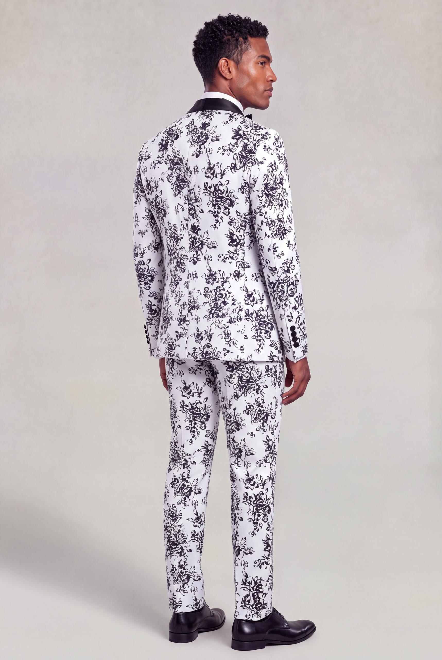 Rear three-quarter full-body view of a white and black floral formal suit with matching trousers from Gentleman's Guru
