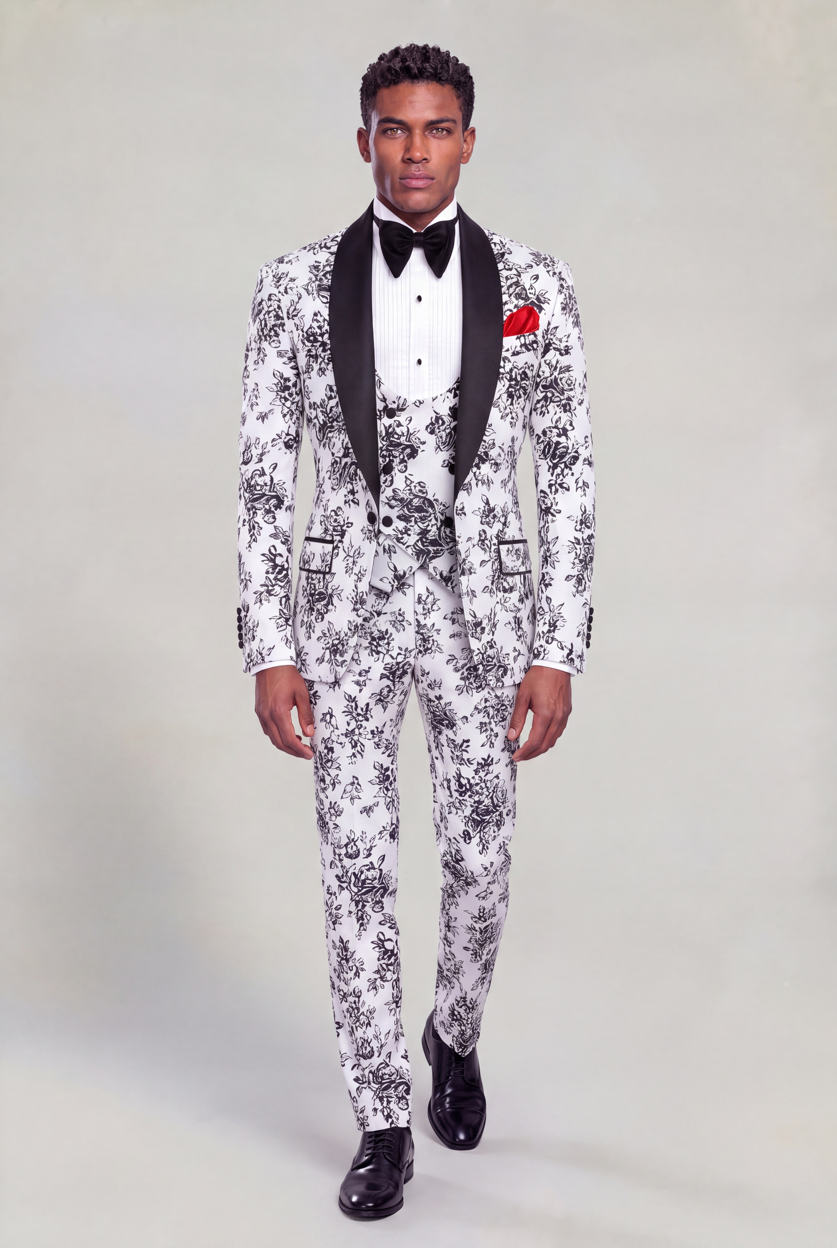 Full-length front walking view of a white and black floral prom tuxedo with matching trousers and black dress shoes from Gentleman's Guru