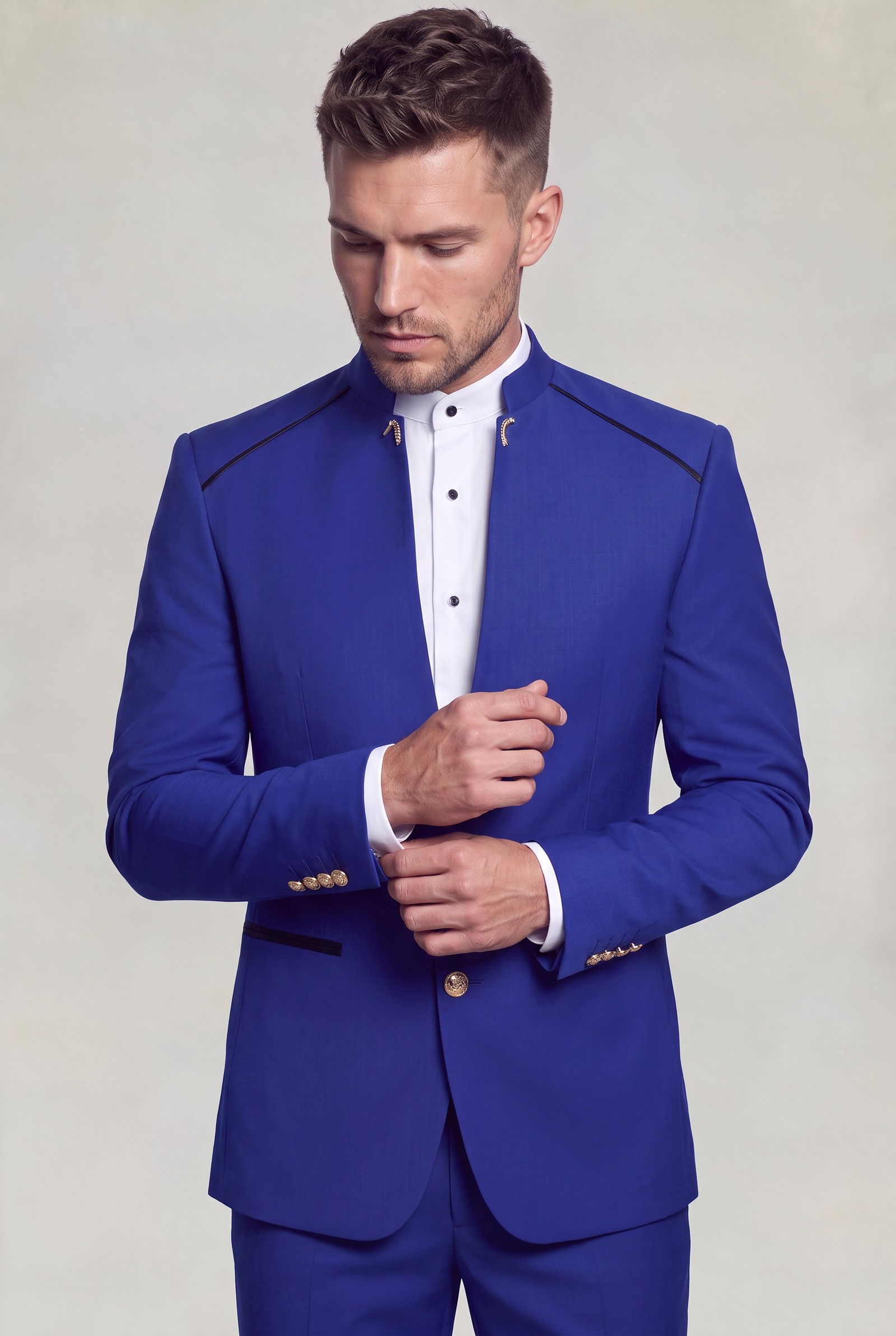 Blue mandarin collar groom jacket with gold cuff buttons in a cuff-adjusting pose