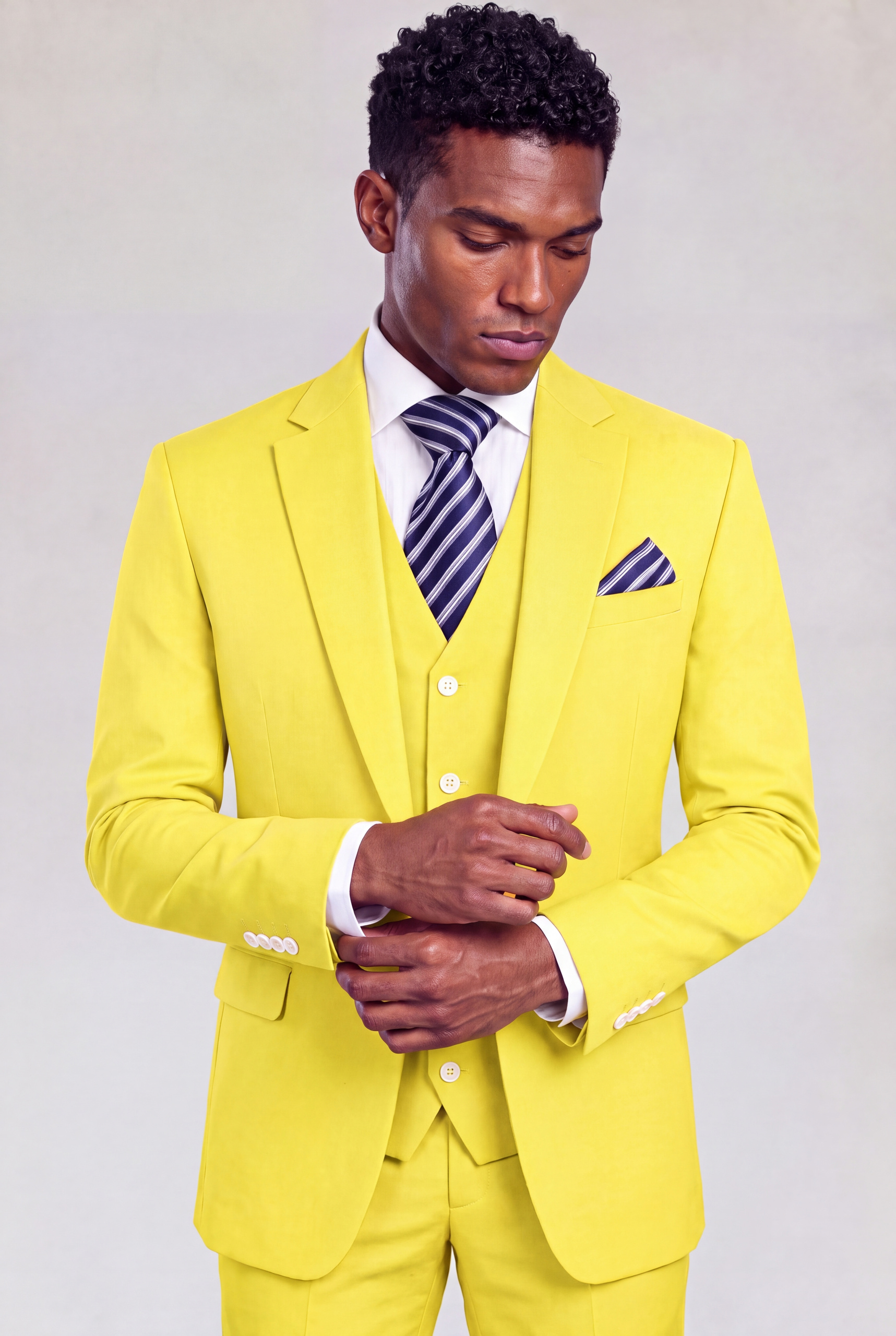 Model adjusting his cuff in a yellow wedding suit with a navy striped tie from Gentleman's Guru