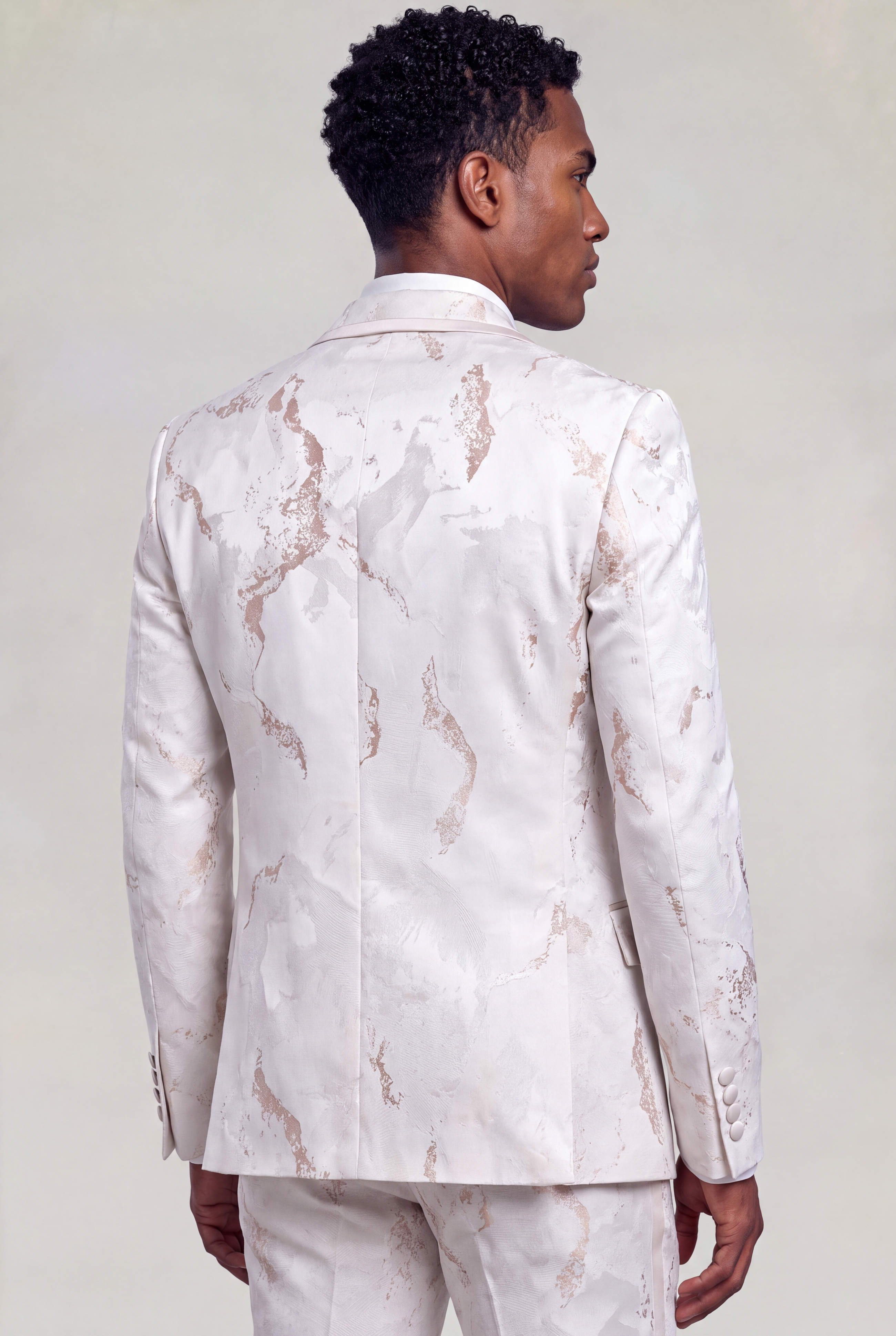 Three-quarter back view showing the rose gold abstract pattern and tailored shape of the ivory tuxedo jacket from Gentleman's Guru