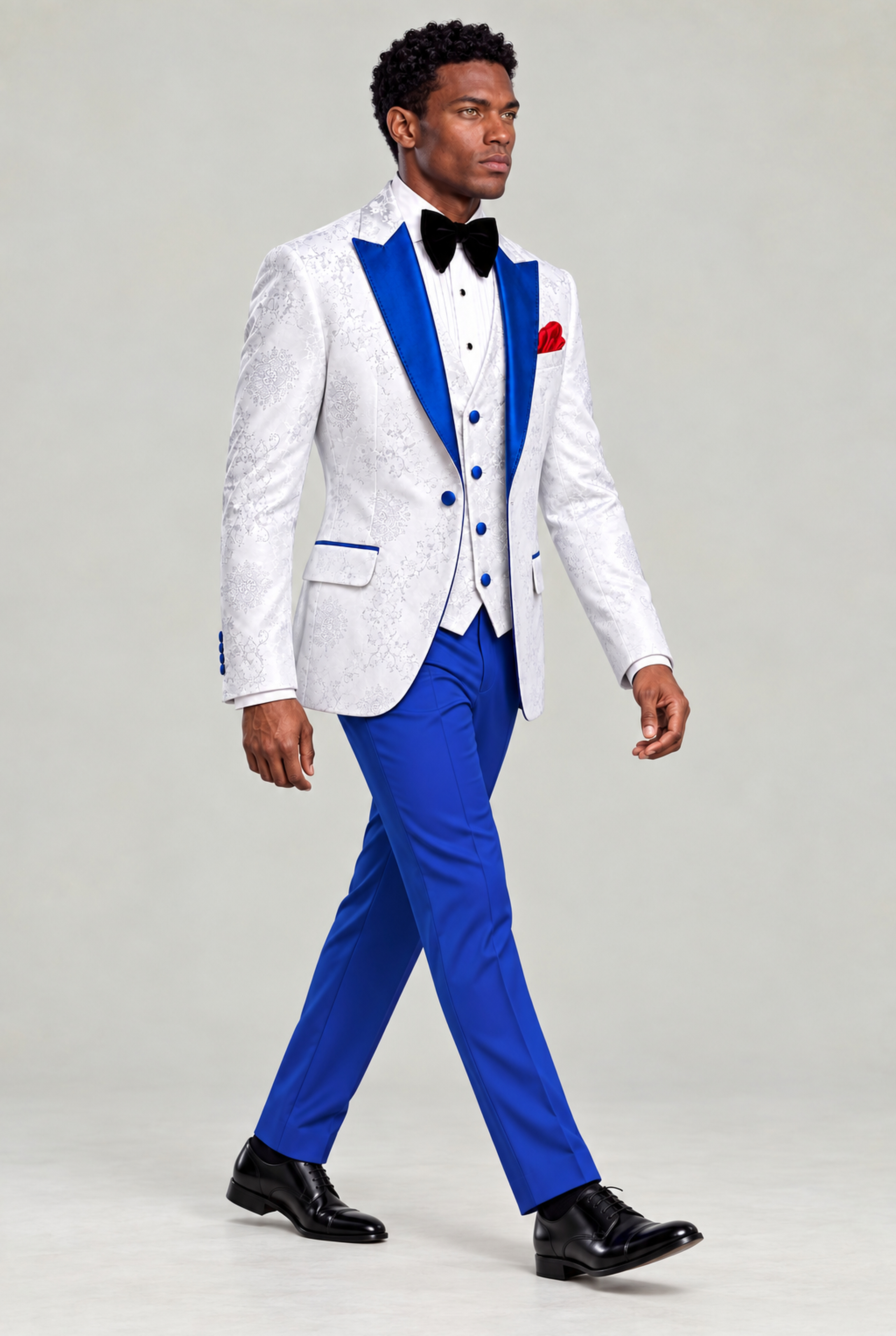 Full-body walking pose looking off camera in a white floral evening jacket, blue trousers and black shoes from Gentleman's Guru