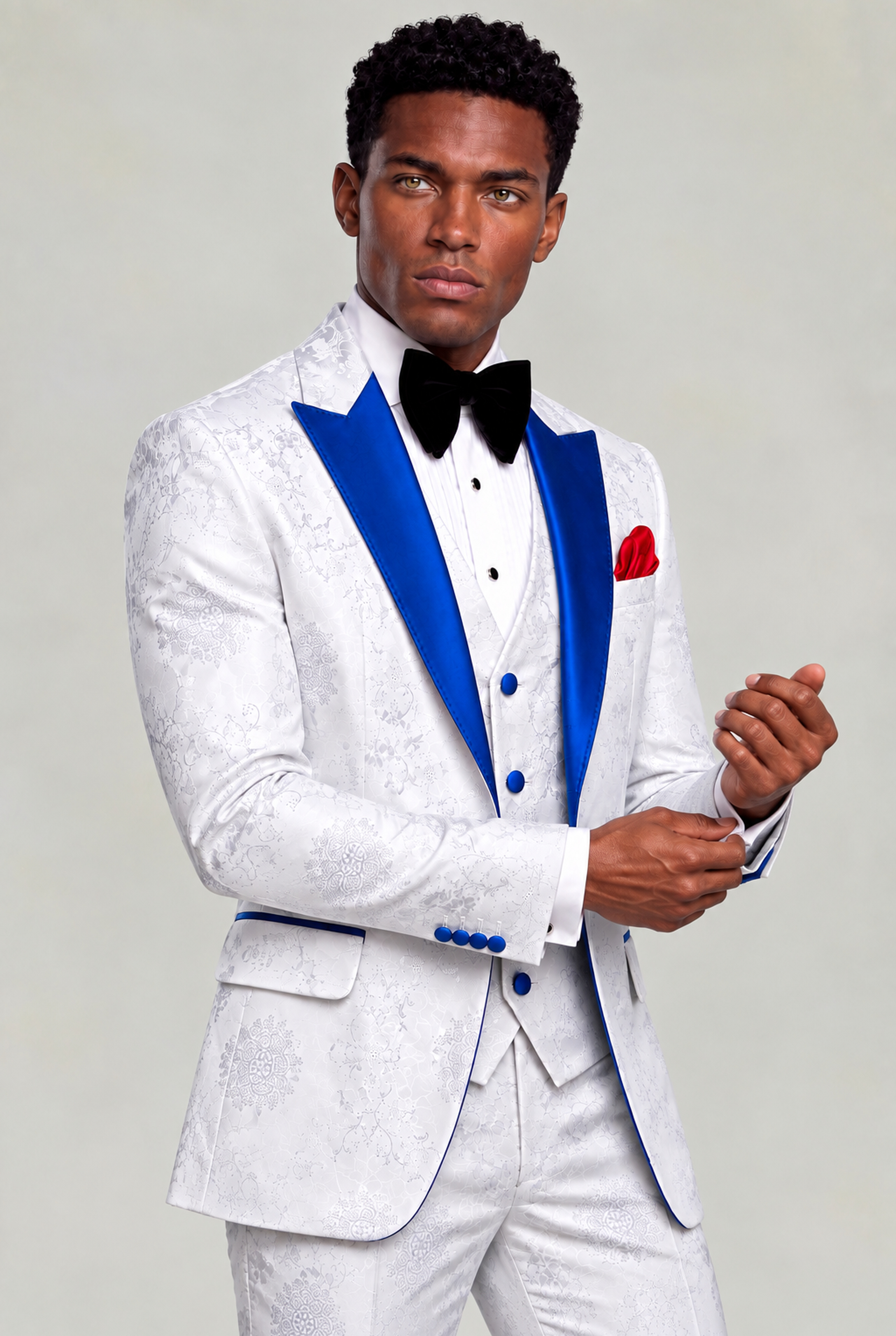 Model adjusting his cuff in a white floral wedding tuxedo with royal blue satin lapels from Gentleman's Guru