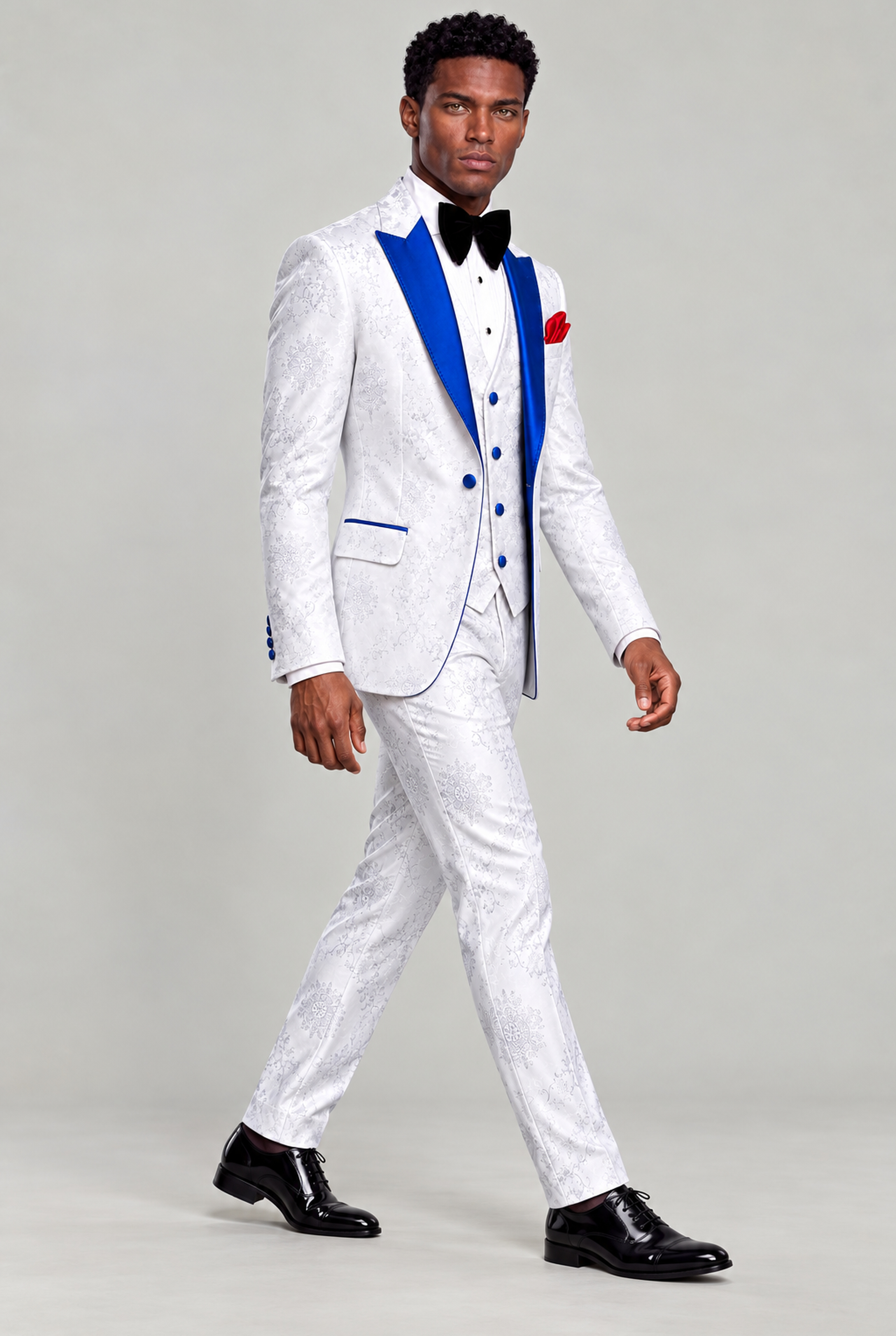 Full-length side walking pose in the white floral three-piece groom tuxedo with black formal shoes from Gentleman's Guru