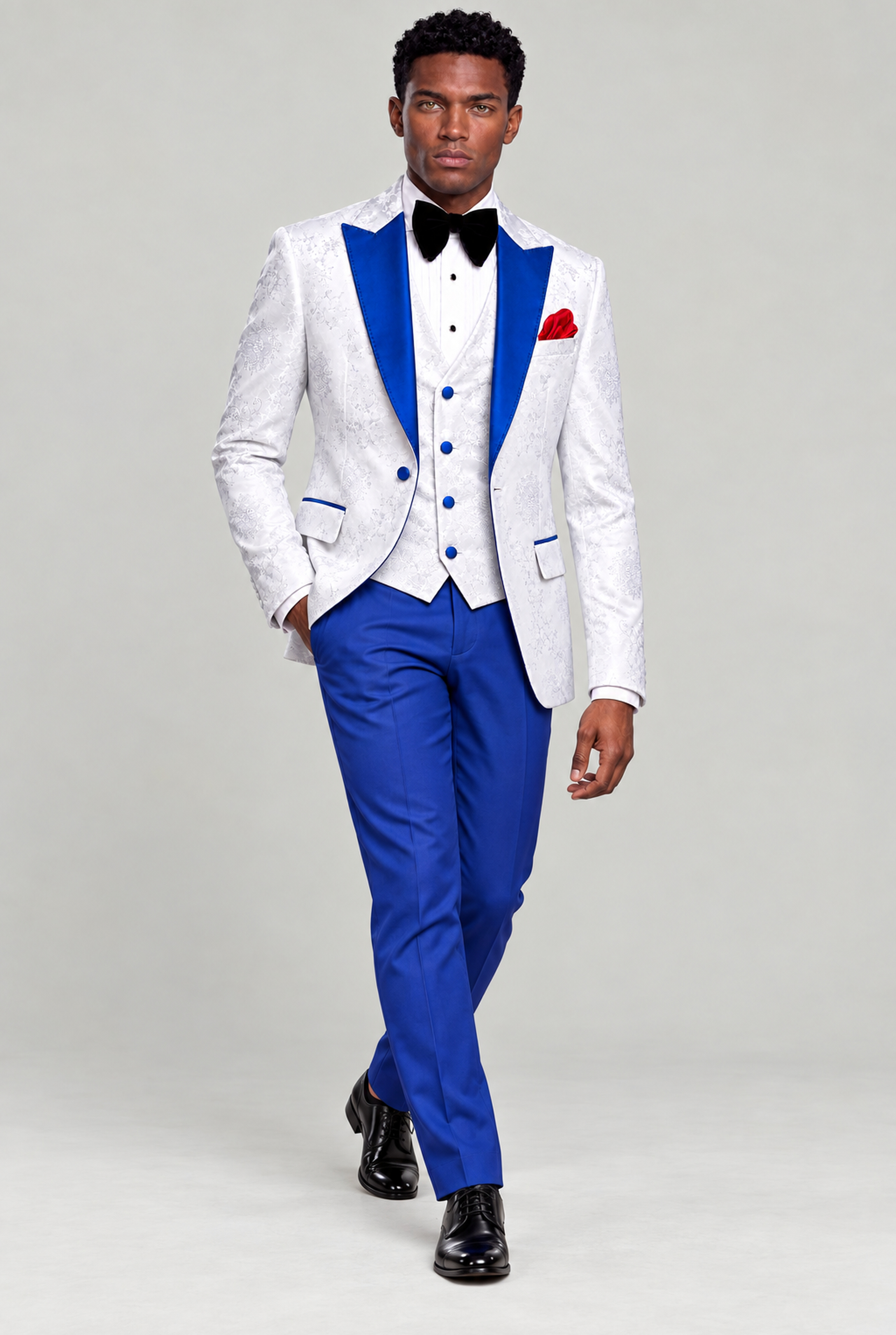Full-length walking view of the white floral tuxedo with solid blue pants and black dress shoes from Gentleman's Guru