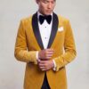 Asian male model adjusting his cuff in a gold velvet tuxedo jacket with black shawl lapels