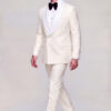 Side walking view of a closed double breasted cream tuxedo with matching patterned pants and black dress shoes from Gentleman’s Guru