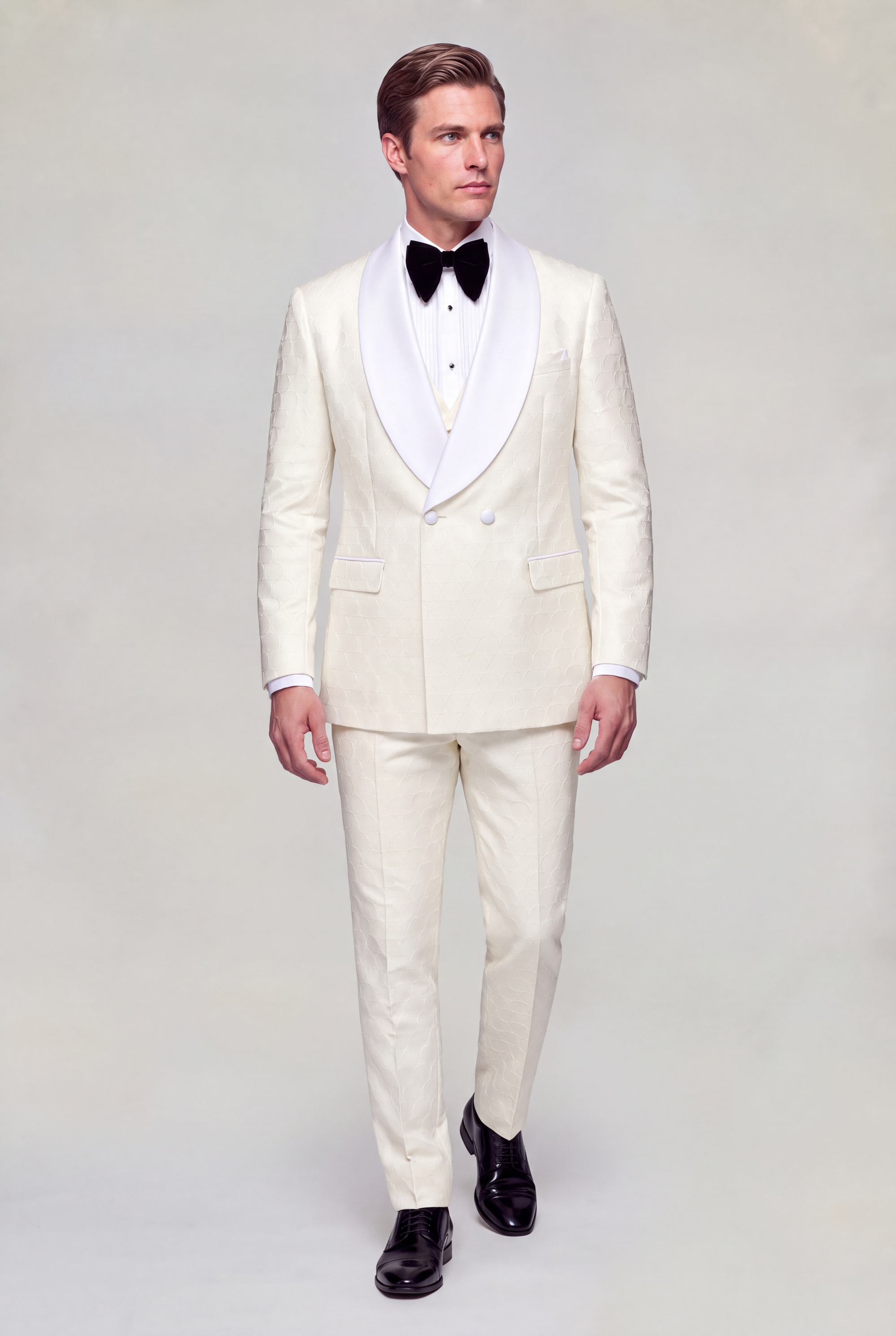 Full length front walking view of a cream three piece tuxedo with matching trousers and black dress shoes from Gentleman’s Guru
