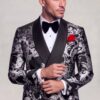 Black and silver paisley tuxedo in a side-angle cuff-adjusting pose