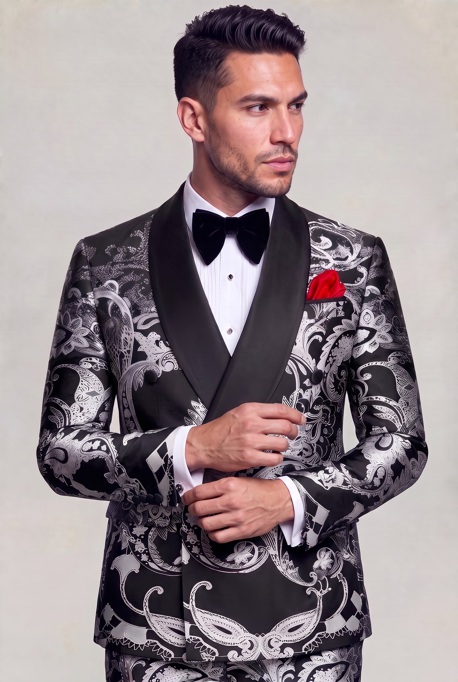 Black and silver paisley tuxedo in a side-angle cuff-adjusting pose