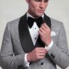 Model adjusting the houndstooth sleeve cuff of a grey double-breasted tuxedo
