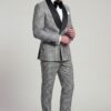 Full-length view of grey houndstooth tuxedo with matching trousers, model adjusting sleeve cuff