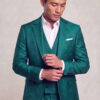 Model looking down while adjusting a cuff in a teal floral suit with matching trousers