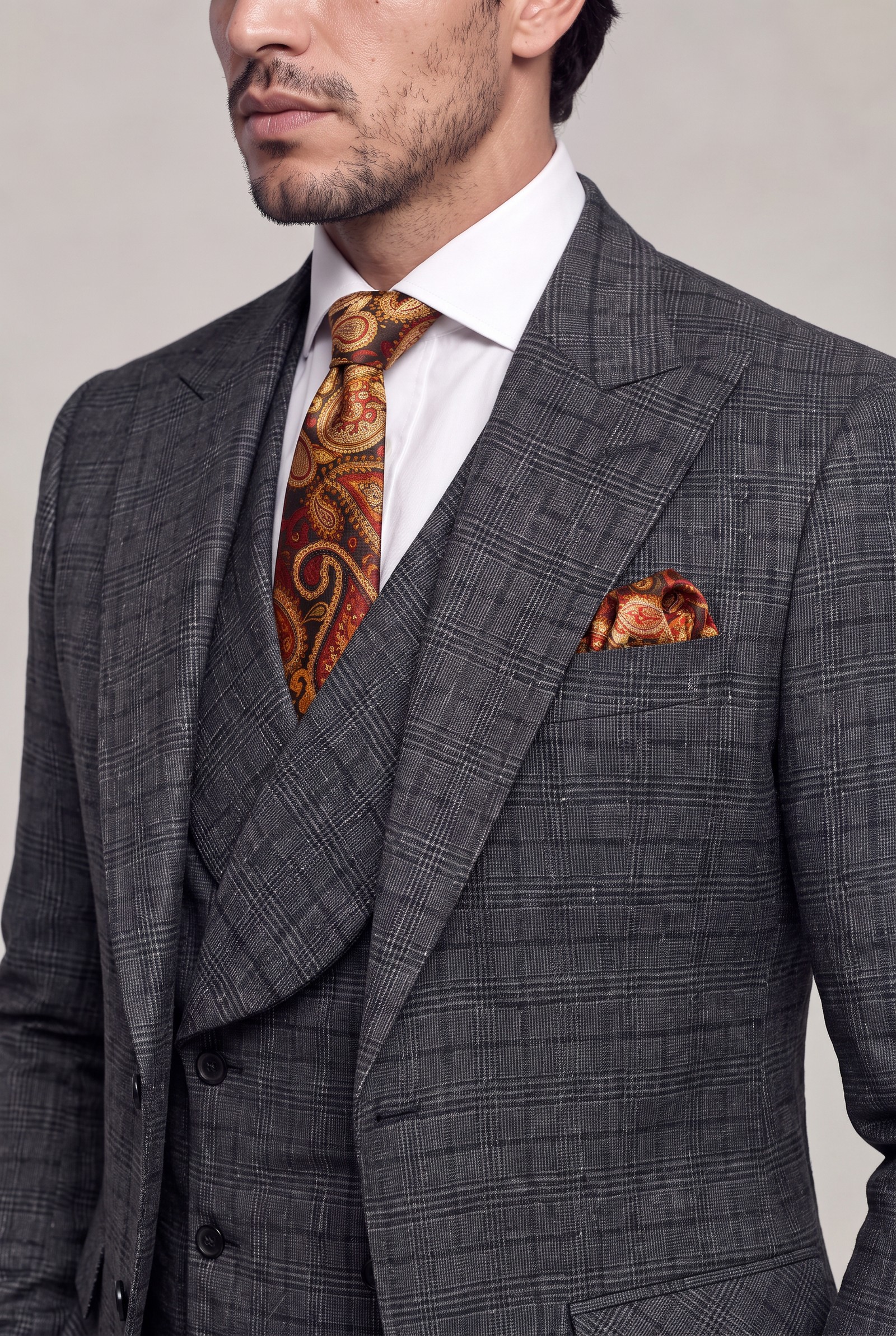Close-up of dark grey plaid peak lapels with paisley tie and pocket square